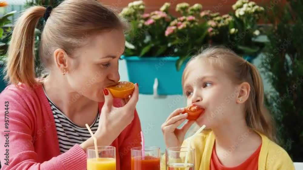 Family eating tomato and orange and looking at camera Family eating tomato and orange and looking at camera