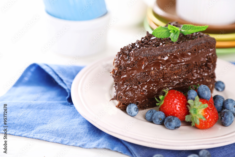 Chocolate cake with chocolate cream and fresh berries on plate, on wooden background Chocolate cake with chocolate cream and fresh berries on plate, on wooden background