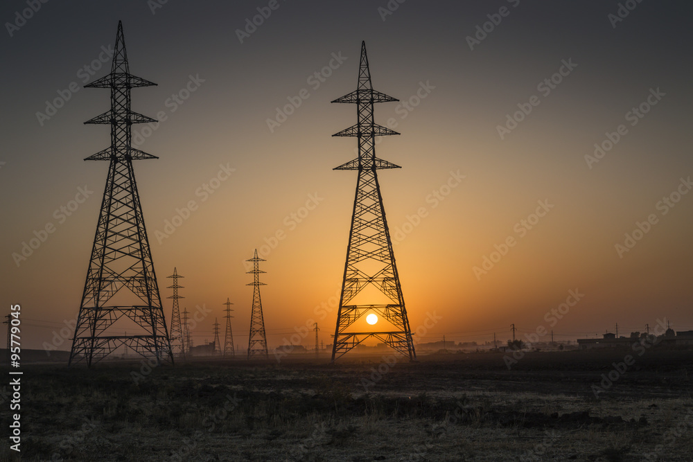 Tow huge power transmission power tower in Iraqi desert during sunrise 