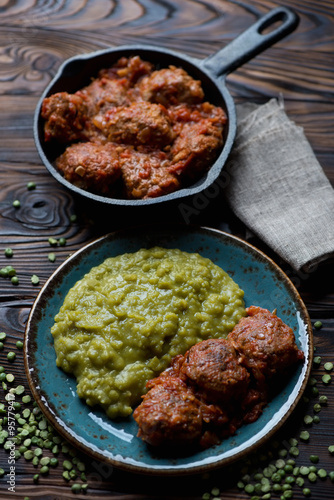 Meatballs in tomato sauce with boiled green peas, studio shot