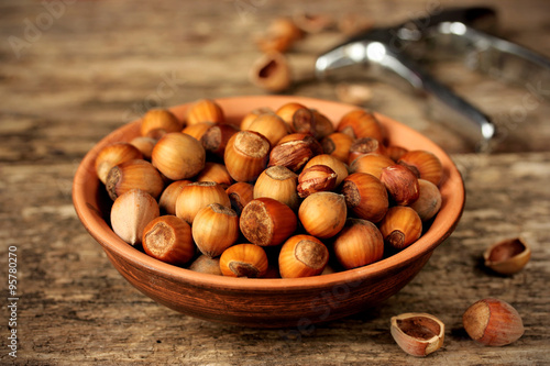 Hazelnuts in a bowl on wooden background, selective focus
