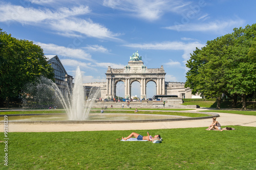Hot summer in Brussels park of Cinquantenaire with unidentified people enjoying the sun. This monument has been raised to celebrate Belgium's independence