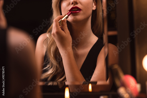 Flirtatious female using red lipstick