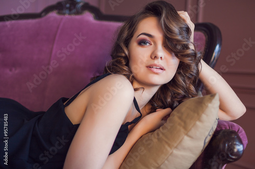 Beautiful luxurious woman on a purple vintage couch