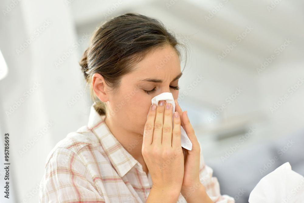 Young woman with cold blowing her nose Young woman with cold blowing her nose
