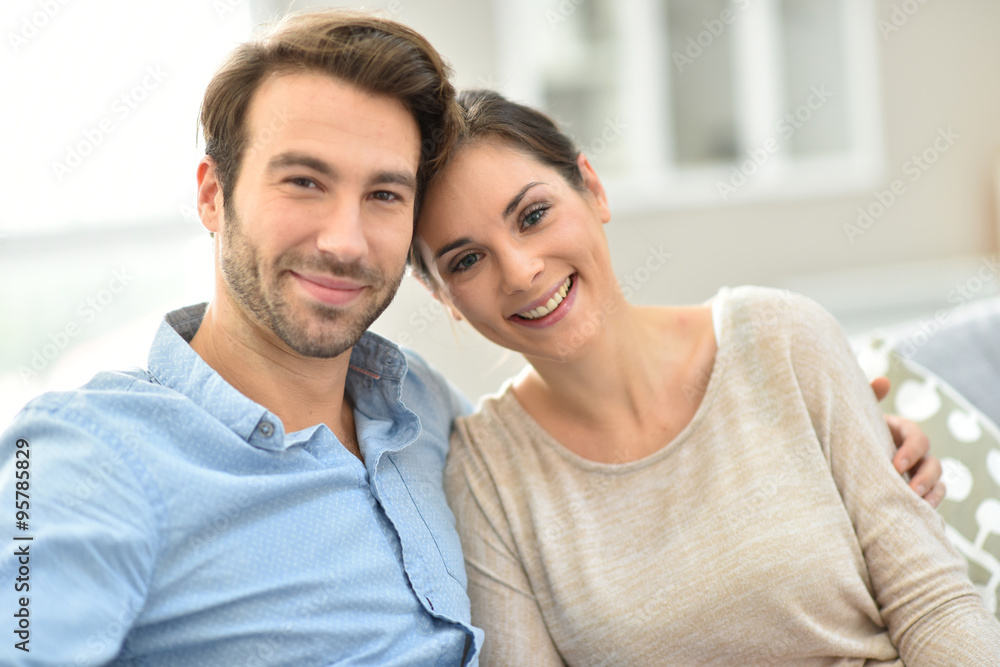 Young smiling couple sitting in sofa at home