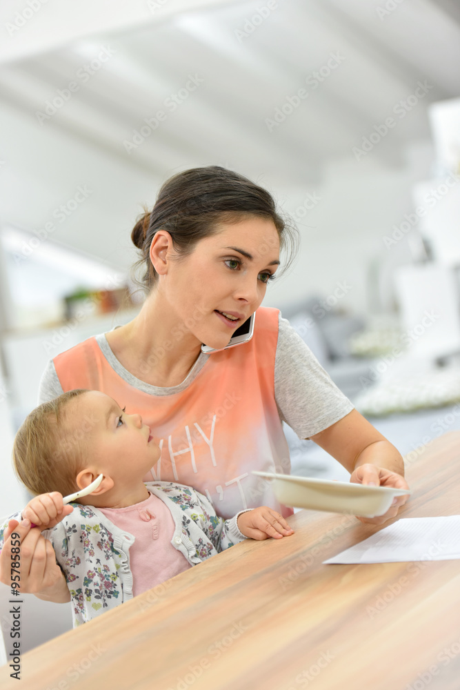 Busy mother on the phone feeding baby a the same time Busy mother on the phone feeding baby a the same time