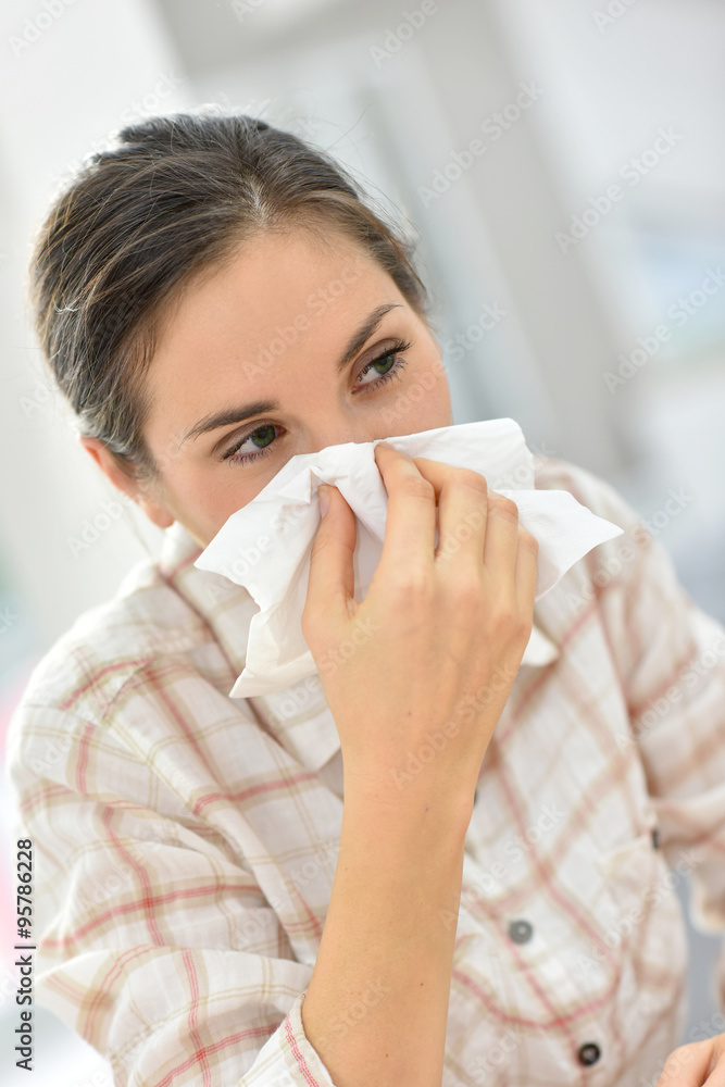 Young woman with cold blowing her nose Young woman with cold blowing her nose