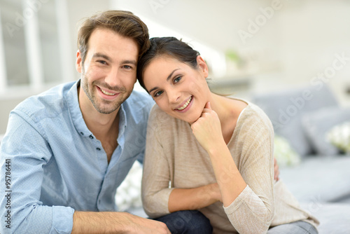 Young smiling couple sitting in sofa at home © goodluz