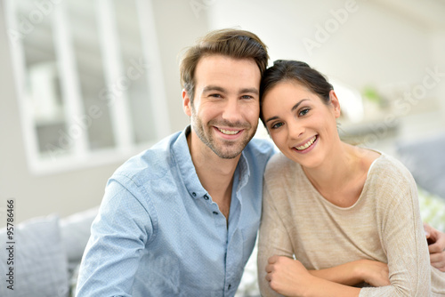 Young smiling couple sitting in sofa at home © goodluz