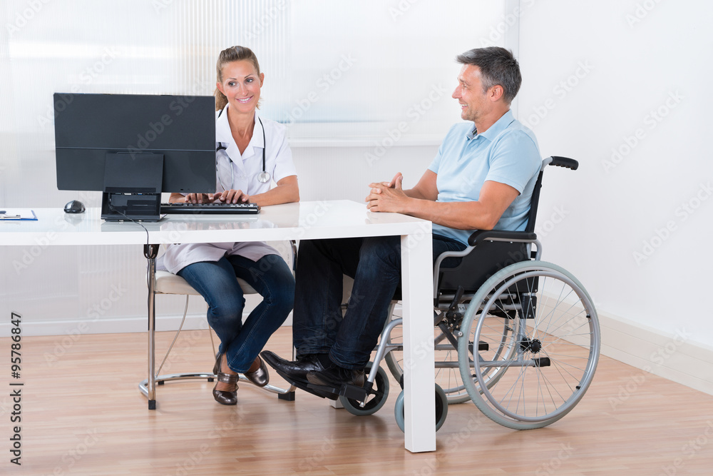 Man Sitting On A Wheelchair Consulting With Doctor Man Sitting On A Wheelchair Consulting With Doctor