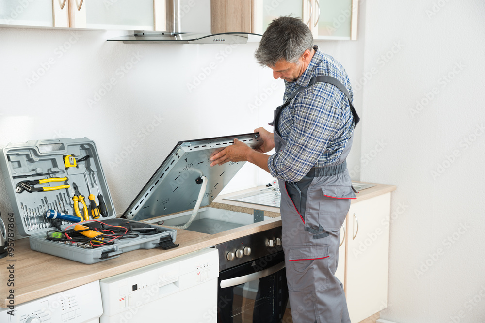 Repairman Examining Stove In Kitchen StockFoto Adobe Stock