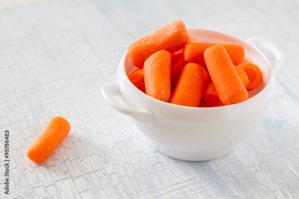 Baby carrot sticks in white bowl Baby carrot sticks in white bowl