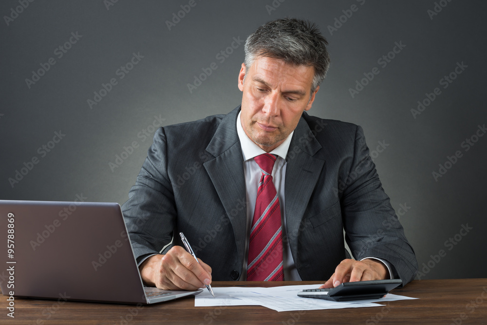 Businessman Checking Bills At Desk Businessman Checking Bills At Desk