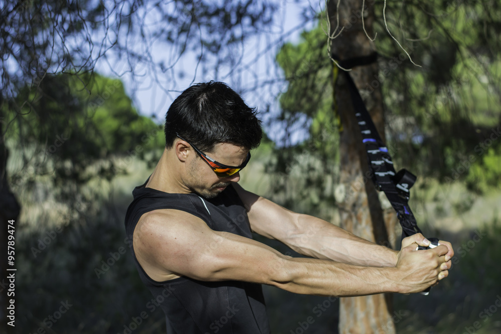 Strong man making triceps using straps suspension