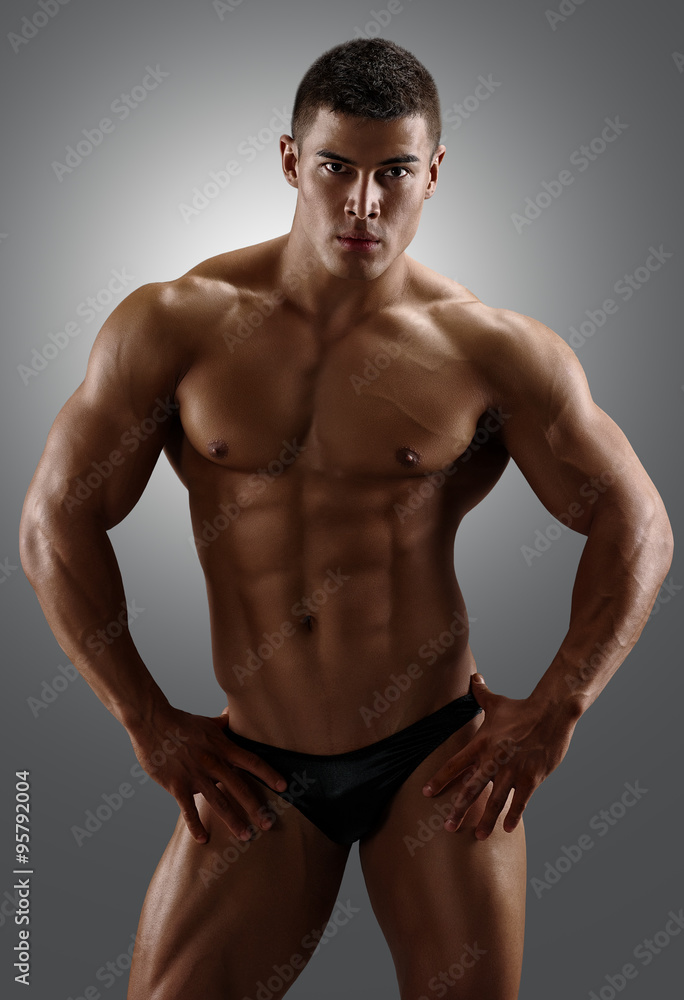 Bodybuilder posing. Handsome power athletic male. Fitness muscular body on gray background Bodybuilder posing. Handsome power athletic male. Fitness muscular body on gray background