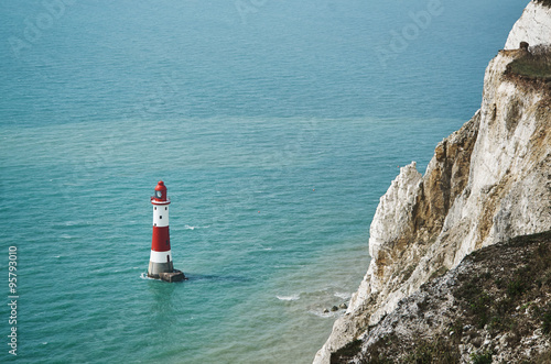 Red and white lighthouse in the sea near rock