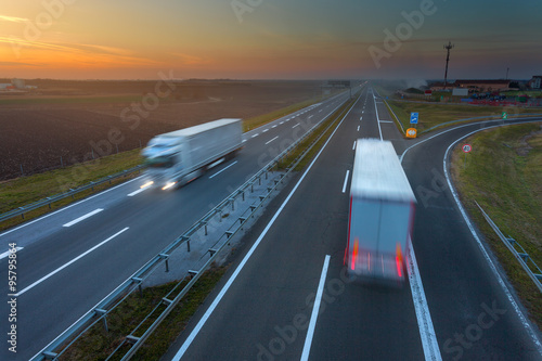 Driving trucks in motion blur on the highway at sunset