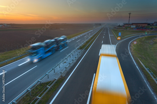 Two trucks in motion blur on the freeway at sunset