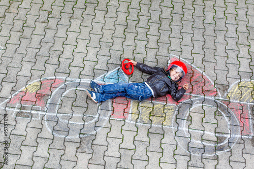 Little boy having fun with race car drawing with chalks photo