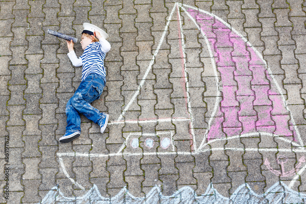 Little kid boy having fun with ship picture drawing with chalk Little kid boy having fun with ship picture drawing with chalk