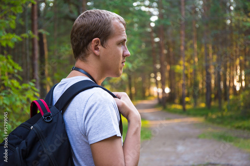 side view of man with backpack hiking in forest