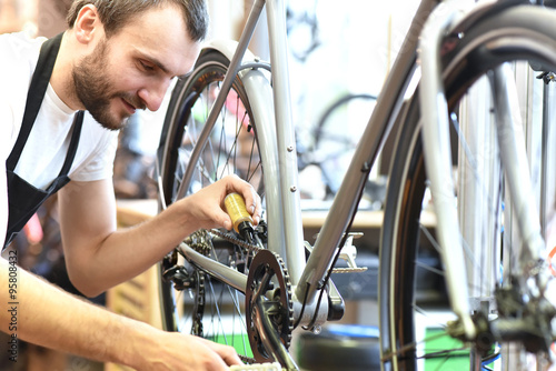 Fotografía Mechaniker repariert Fahrrad in einer Werkstatt - ölen der Kette // mechanic rep
