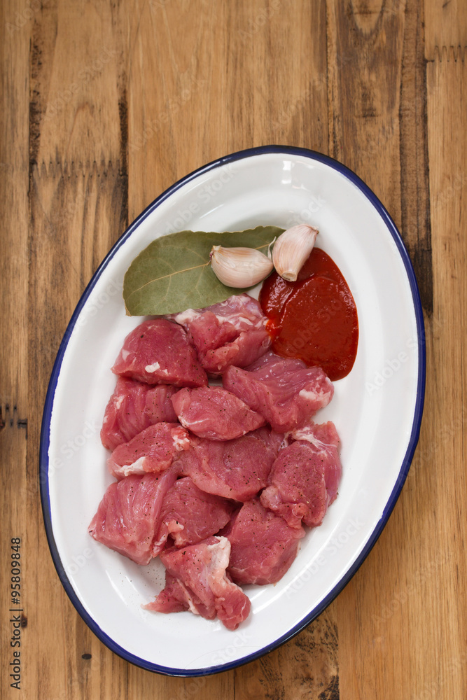 raw meat with garlic on dish on wooden background raw meat with garlic on dish on wooden background