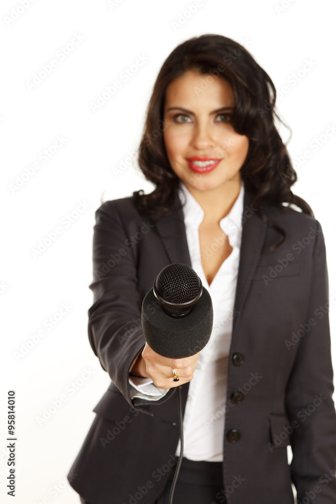 A young woman holds out her microphone to viewer. Focus is on the microphone. A young woman holds out her microphone to viewer. Focus is on the microphone.
