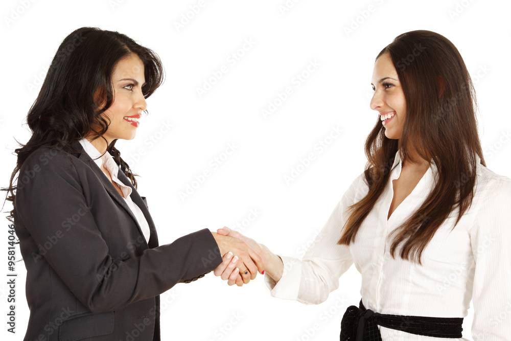 Two businesswomen shaking hands. Women smiling and looking at each other. Two businesswomen shaking hands. Women smiling and looking at each other.