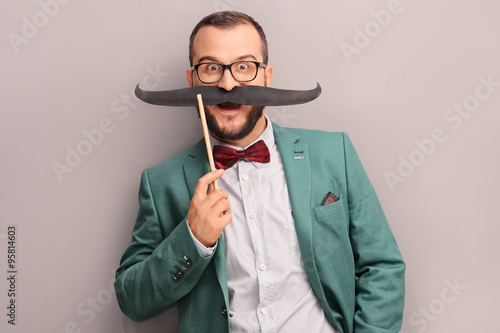 Excited man holding a fake mustache on his face photo