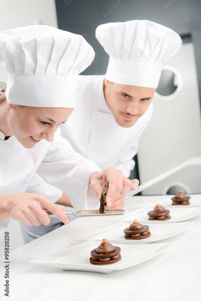 portrait of a cheerful young woman professional pastry cook at work in kitchen decorating a chocolate dessert portrait of a cheerful young woman professional pastry cook at work in kitchen decorating a chocolate dessert