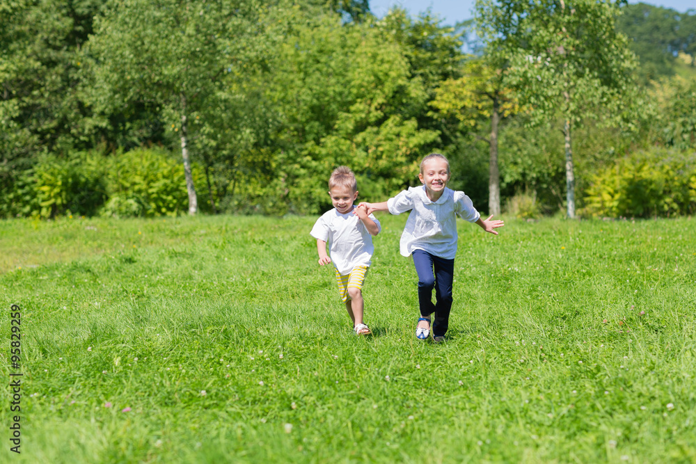 Happy brother and sister running on the grass