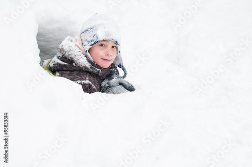 young boy playing out in a snowfort on a winter day photo