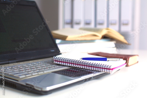 Office table with blank notepad and laptop 