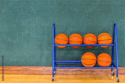 Basketballs in Storage Rack against Wall in Gym Basketball Court.  Copy Space. 