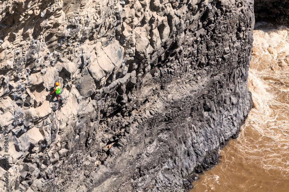Naklejka premium Young Brave Man Climbing Natural Rock Wall