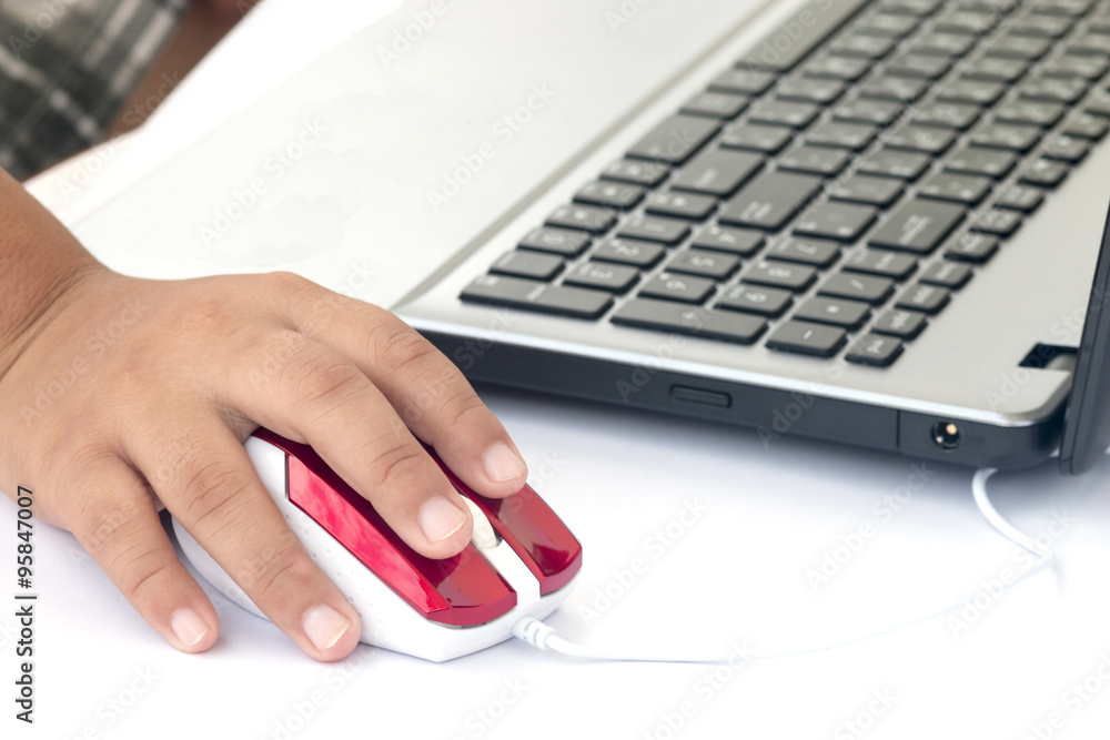 Human hand on computer mouse and Laptop on desk