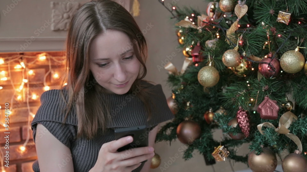 Woman using her mobile phone at christmas at home in the living room Woman using her mobile phone at christmas at home in the living room