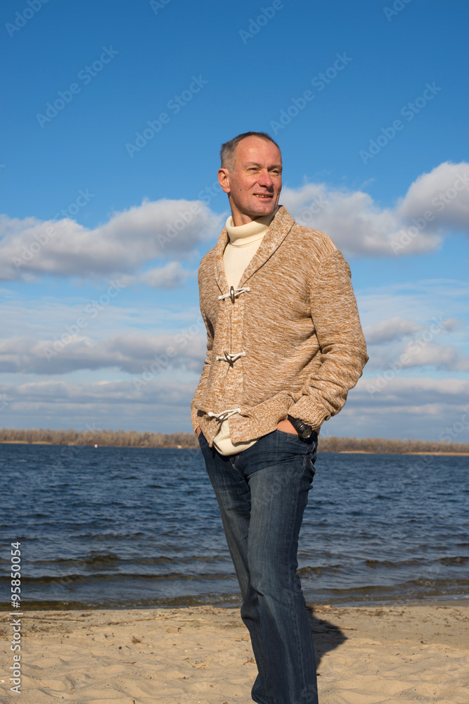 Attractive happy man, wearing casually, walking along the coast,