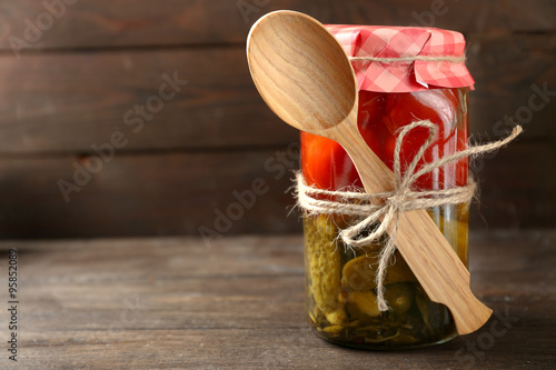 Jar of canned cucumbers and tomatoes on wooden background