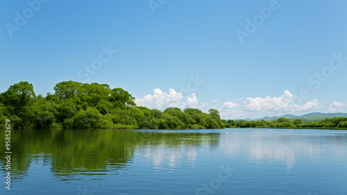 River summer landscape with bright blue sky and clouds