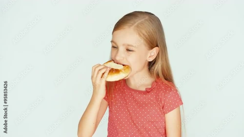 Girl eating a cake with cheese. Child on the white background. Closeup. Thumb up. Ok Girl eating a cake with cheese. Child on the white background. Closeup. Thumb up. Ok