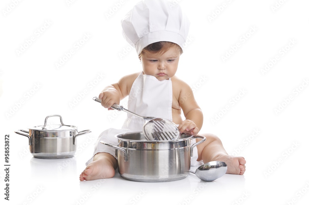 Funny adorable baby boy chef sitting and playing with kitchen equipment Funny adorable baby boy chef sitting and playing with kitchen equipment