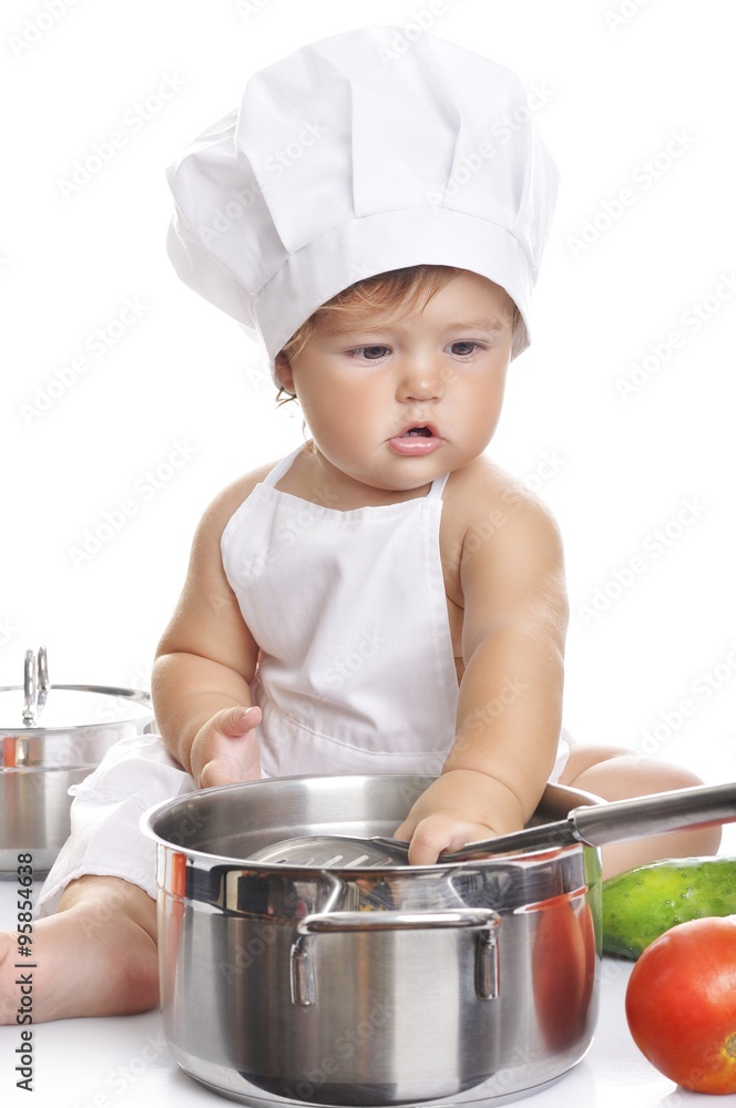 Funny adorable baby boy chef sitting and playing with kitchen equipment Funny adorable baby boy chef sitting and playing with kitchen equipment