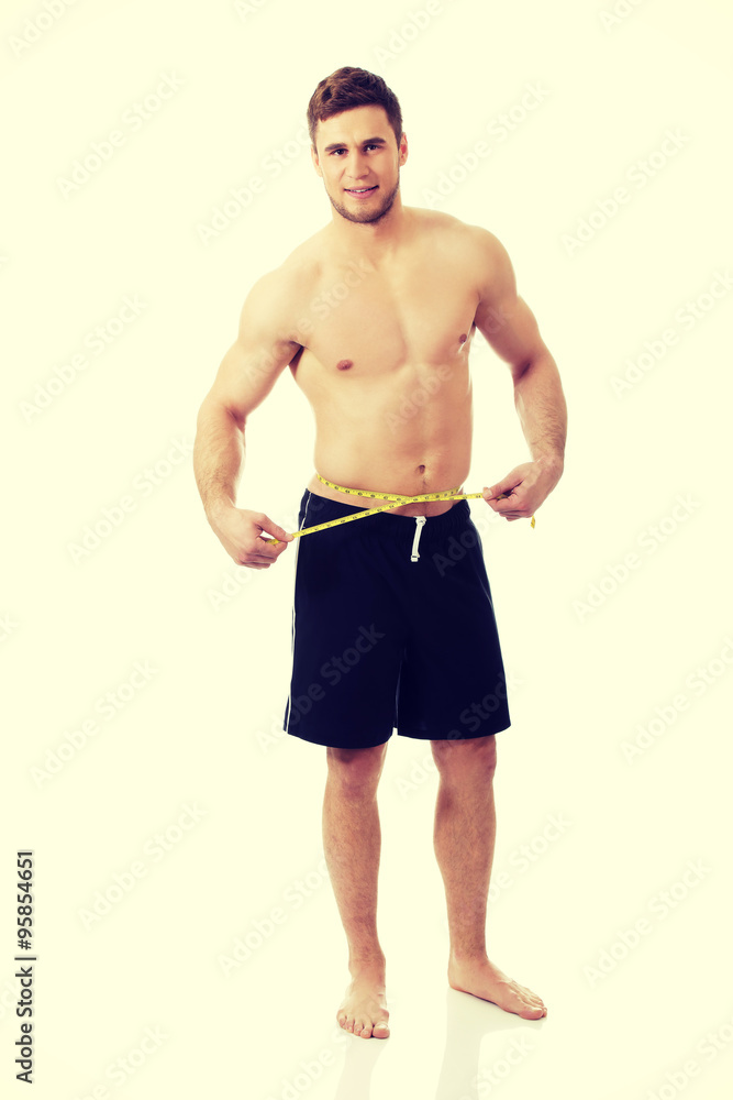 Fototapeta premium Muscular man measuring his belly.