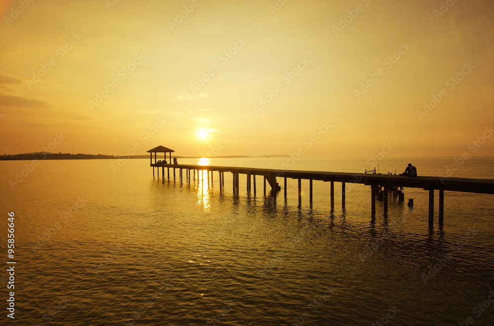 silhouette of a man sitting on the bridge alone during sunset