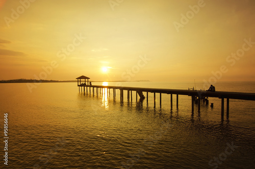 silhouette of a man sitting on the bridge alone during sunset © nelzajamal