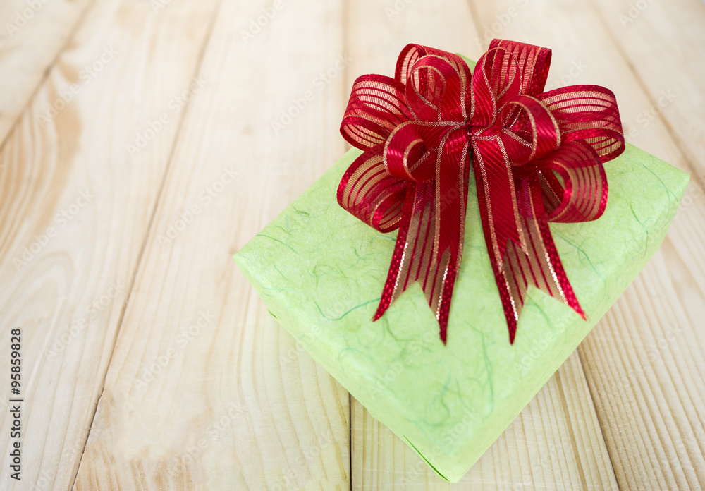 Gift box 1 - One green gift box and red bow on wood background (New Year and Christmas Holiday)