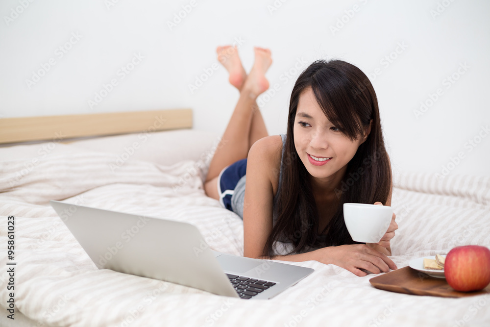 Woman watching the laptop computer and having breakfast Woman watching the laptop computer and having breakfast